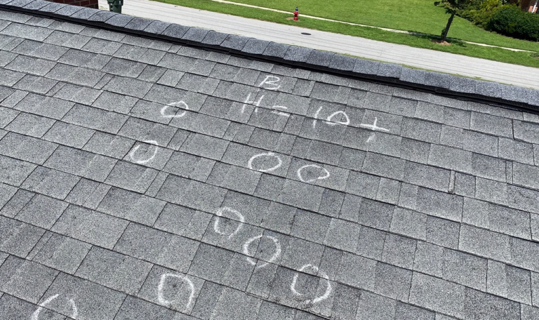 A black singled roof that has been assessed for hail damage on a sunny day.